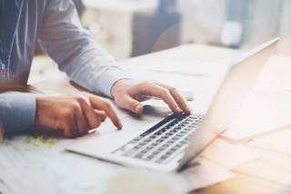 Lähikuva miehestä läppärin äärellä